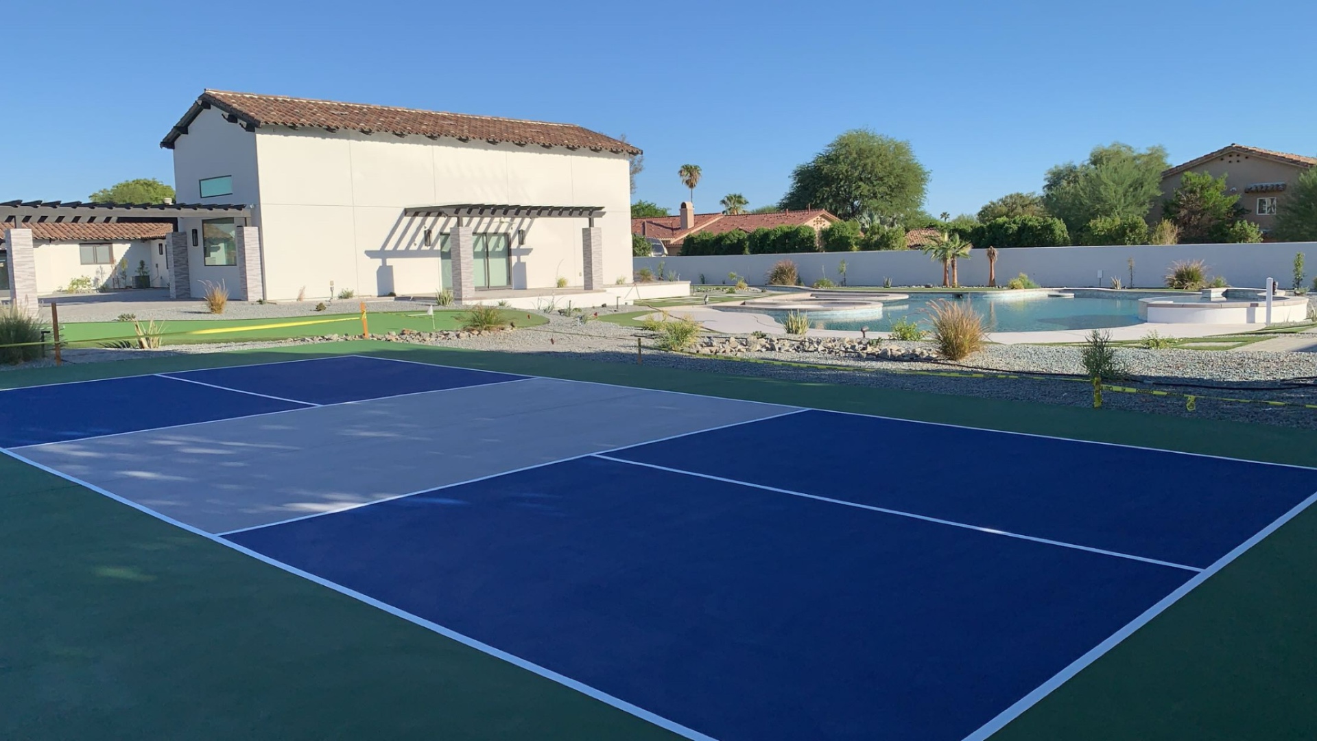 Backyard pickleball court in a desert estate with palm trees and crisp white lines